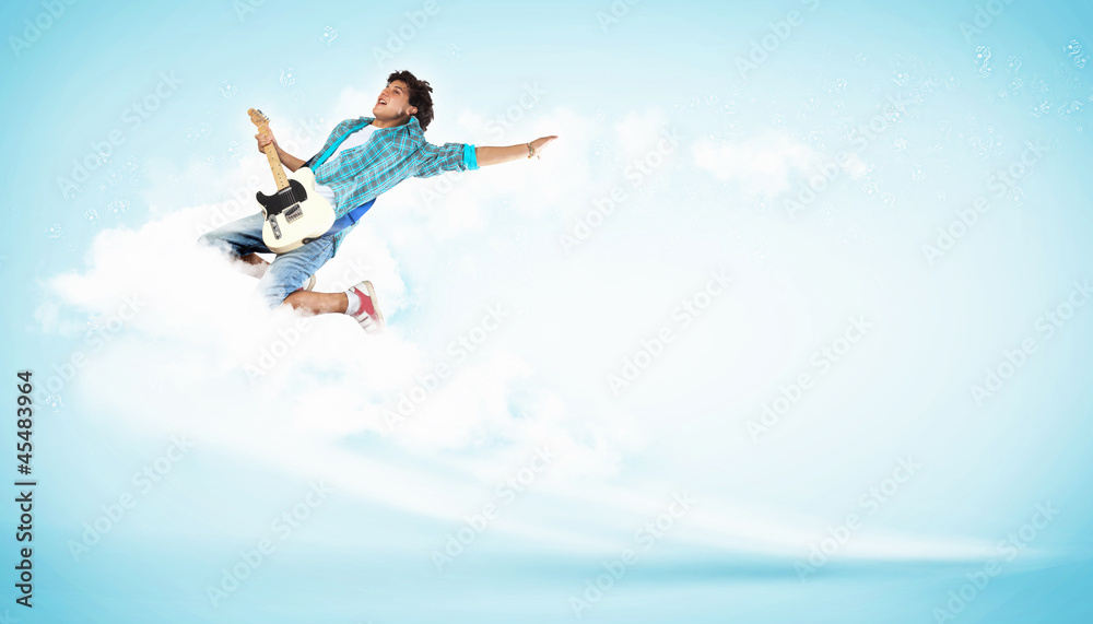 young man playing on electro guitar and jumping