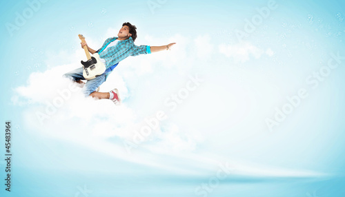 young man playing on electro guitar and jumping