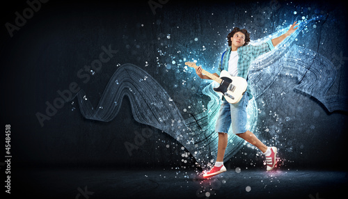 young man playing on electro guitar and jumping © Sergey Nivens