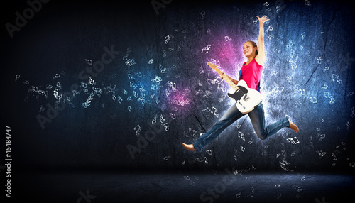 Fototapeta Naklejka Na Ścianę i Meble -  young woman playing on electro guitar and jumping