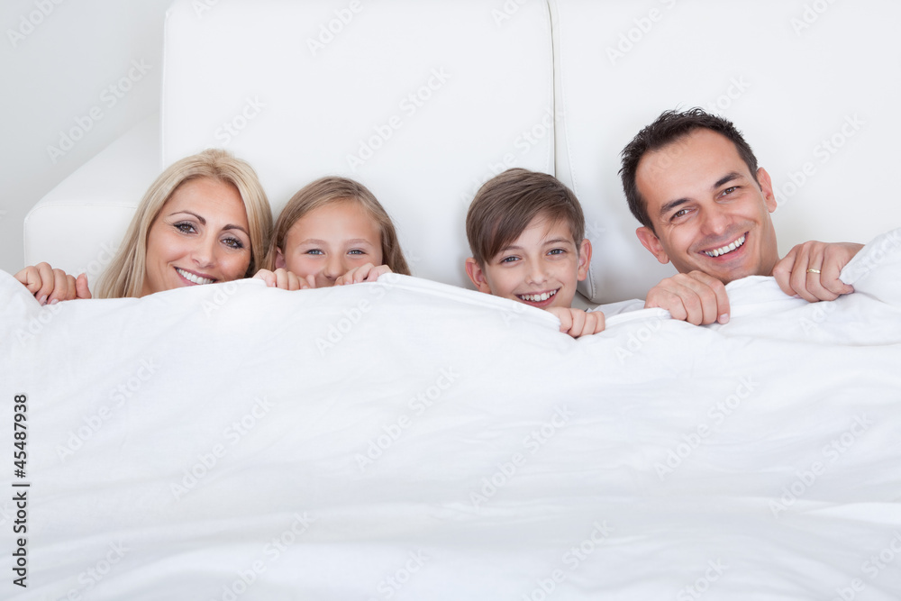 Happy Family With Two Children In Bed Under Cover Happy Family With Two Children In Bed Under Cover