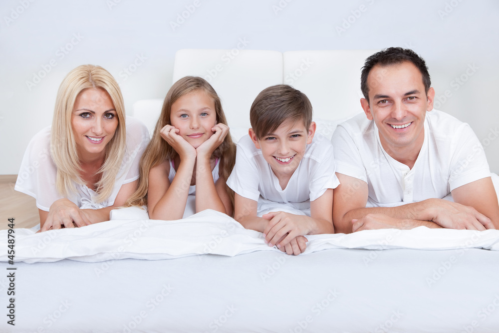 Happy Family With Two Children Lying On Bed Happy Family With Two Children Lying On Bed