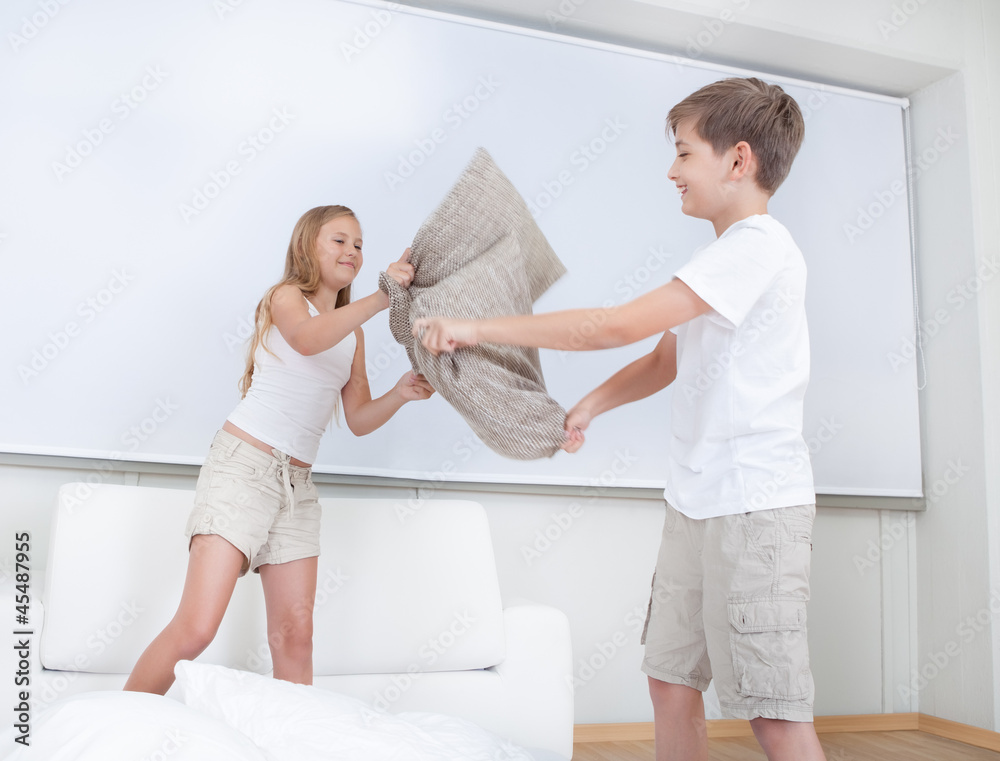 Siblings Having A Pillow Fight Together On Bed Siblings Having A Pillow Fight Together On Bed