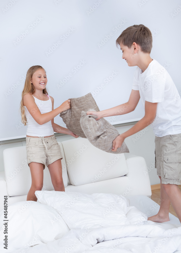 Siblings Having A Pillow Fight Together On Bed Siblings Having A Pillow Fight Together On Bed
