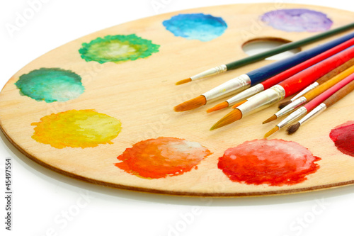 wooden art palette with paint and brushes isolated on white