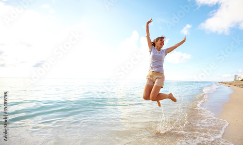 Happy woman jumping on the beach.