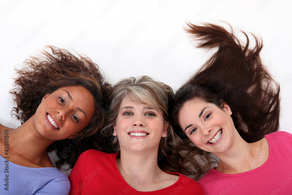 Three happy girls laid on the ground, studio shot Three happy girls laid on the ground, studio shot
