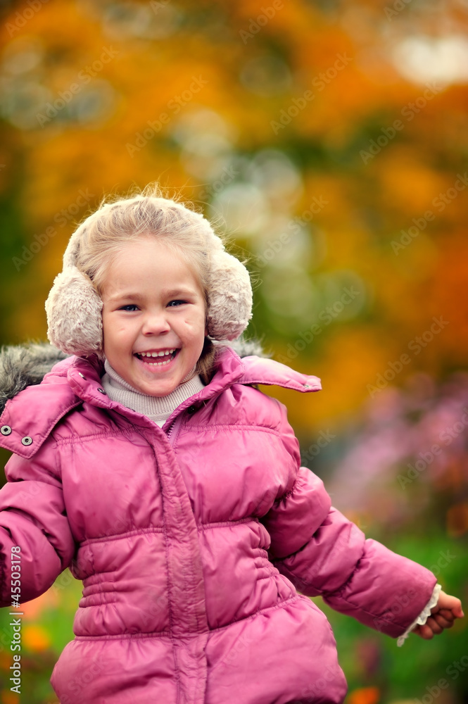 portrait of cute happy girl in warm clothes at autumn background