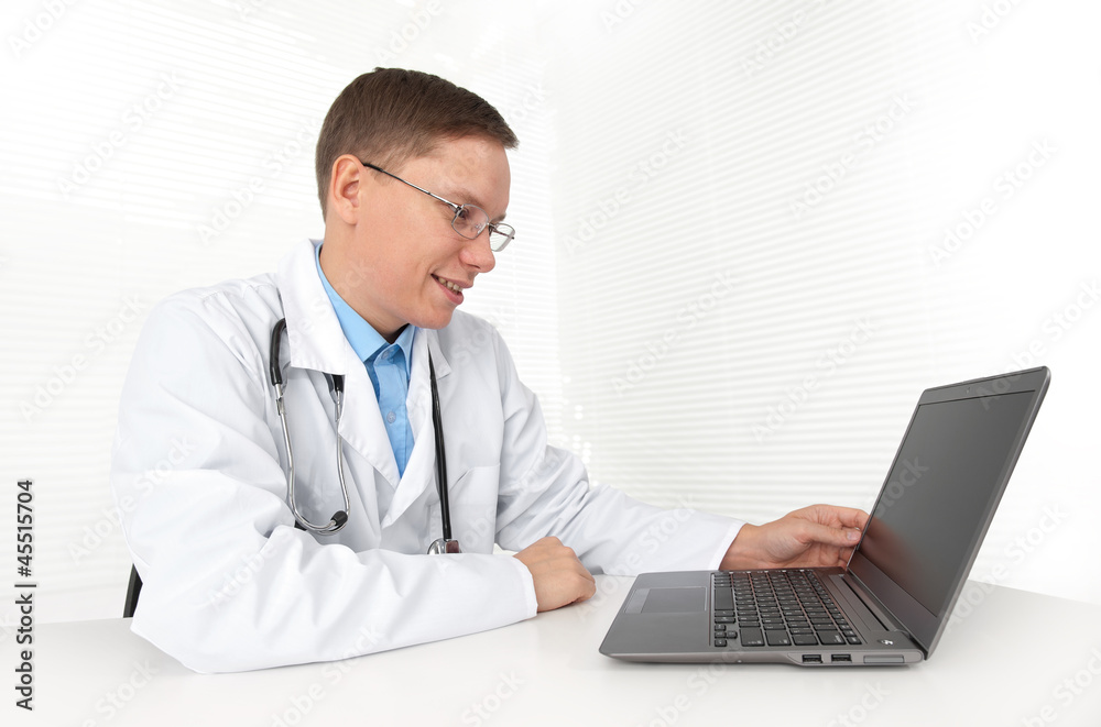 Doctor sitting at his desk with laptop computer Doctor sitting at his desk with laptop computer