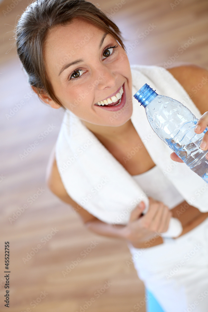 Cheerful fitness girl drinking water after exercising Cheerful fitness girl drinking water after exercising