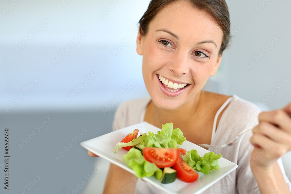 Closeup of cheerful woman eating fresh salad Closeup of cheerful woman eating fresh salad