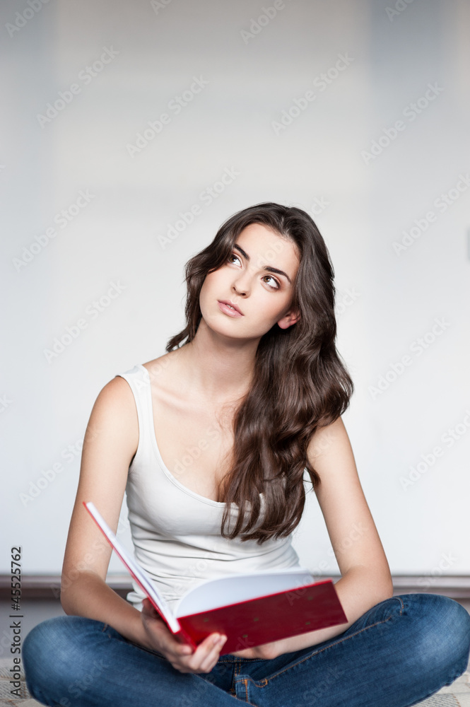 thoughtful female in casual outfit holding red book thoughtful female in casual outfit holding red book
