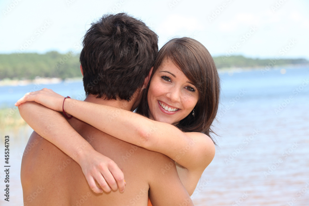 young woman hugging boyfriend at beach young woman hugging boyfriend at beach