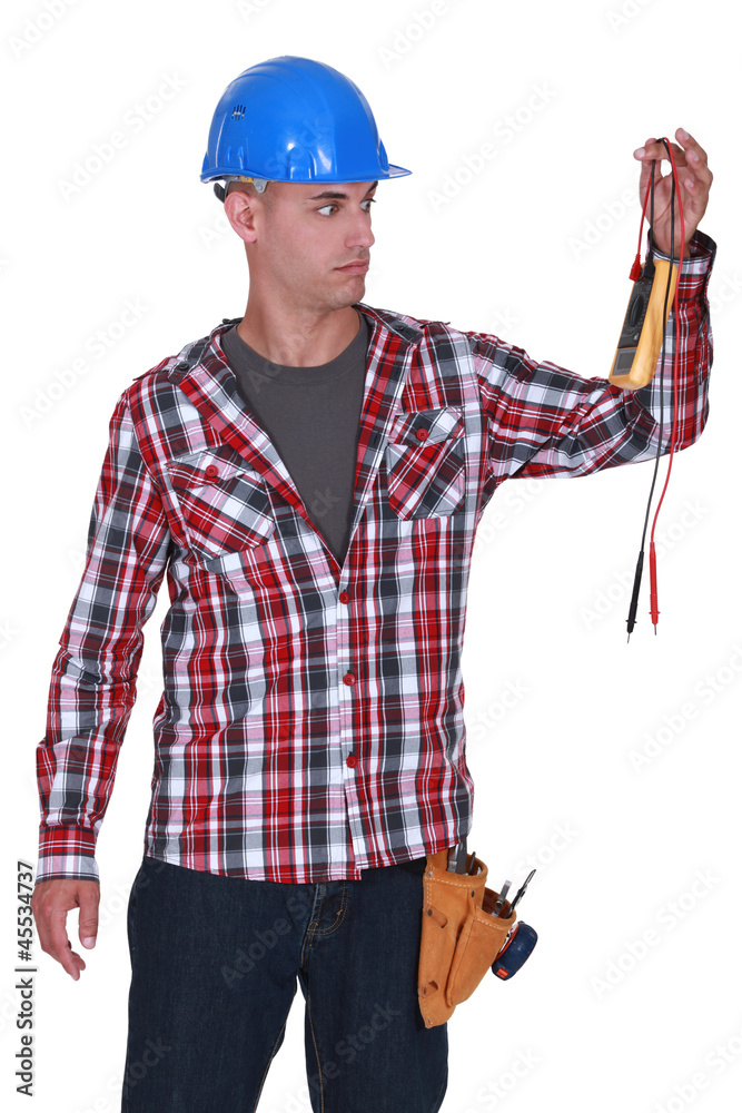 Confused builder holding voltmeter Confused builder holding voltmeter