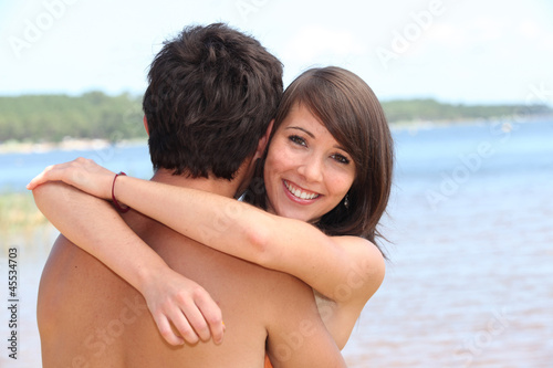 young woman hugging boyfriend at beach