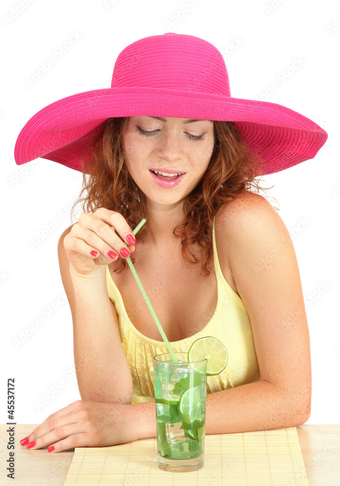 Smiling beautiful girl sitting at the table with beach hat and