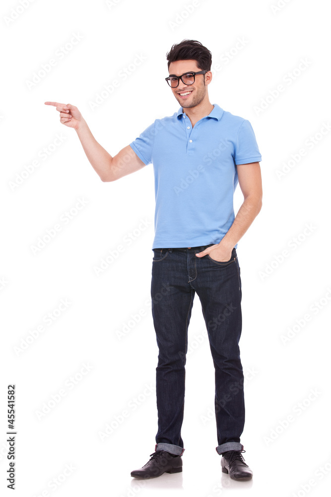 young man pointing with a hand in pocket young man pointing with a hand in pocket