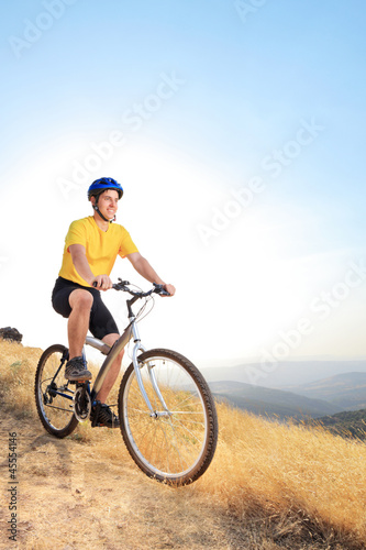 A view of a young biker riding a mountain bike on a sunset