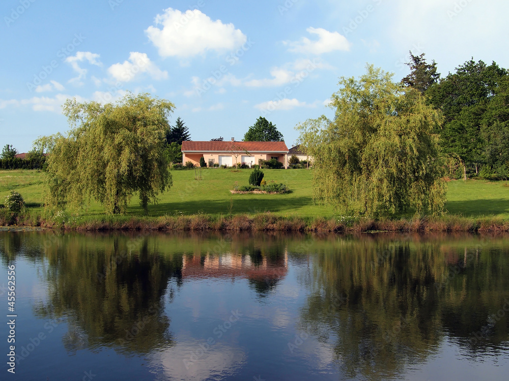 Landscape of a rural french property with a house reflected in the pond Landscape of a rural french property with a house reflected in the pond