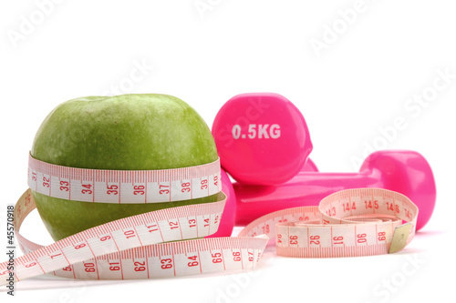 An apple, a measuring tape and dunbbell photo