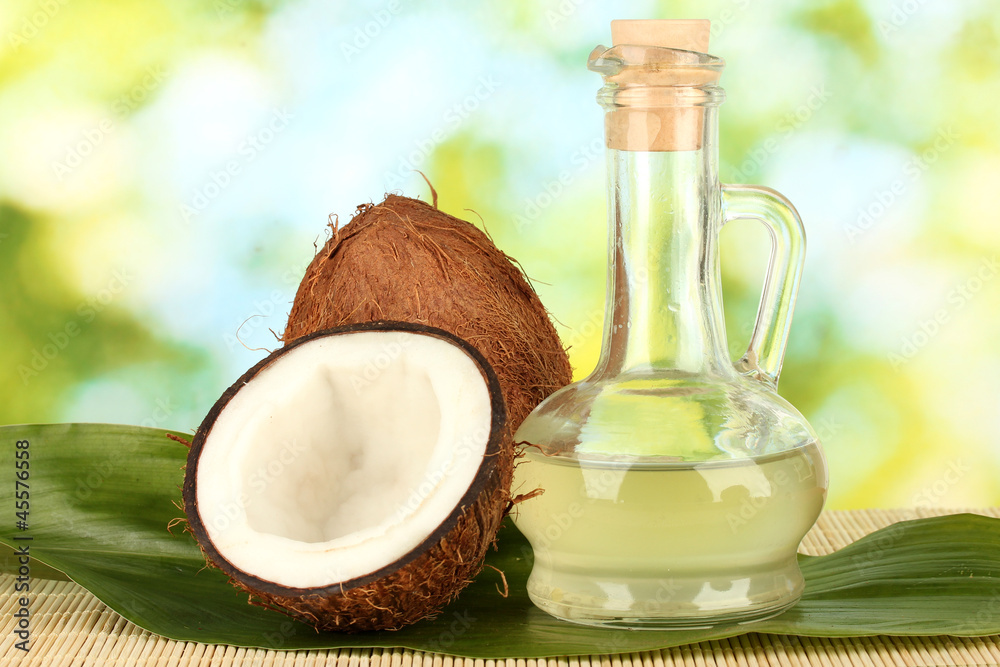 decanter with coconut oil and coconuts on green background decanter with coconut oil and coconuts on green background