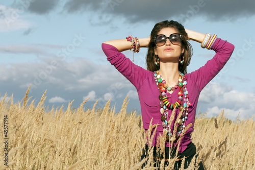 Young woman wearing jewellery and sunglasses in field