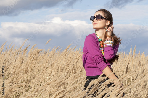 Young fashiooned woman wearing jewellery and sunglasses in field