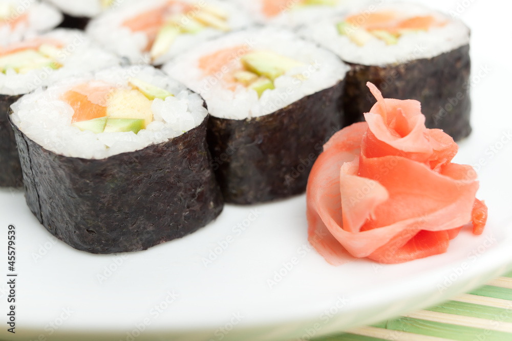 Sushi rolls on the white plate which is on green mat Sushi rolls on the white plate which is on green mat