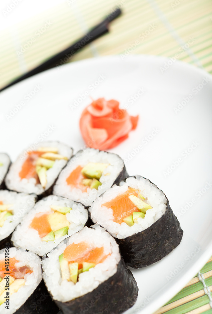 Sushi rolls on the plate with chopsticks on green mat Sushi rolls on the plate with chopsticks on green mat