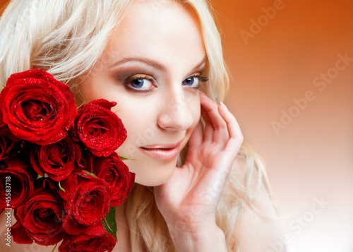 Beautiful girl with red roses in her blond hair...