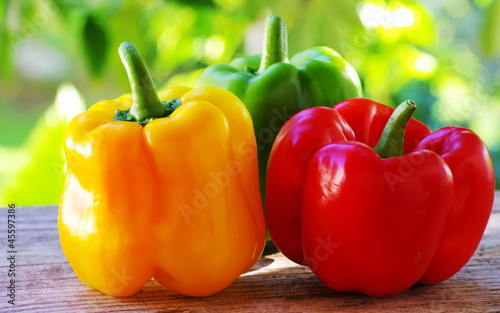Fotografering red, yellow and green pepper on table,green background