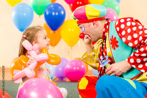 happy child girl and clown playing on birthday party