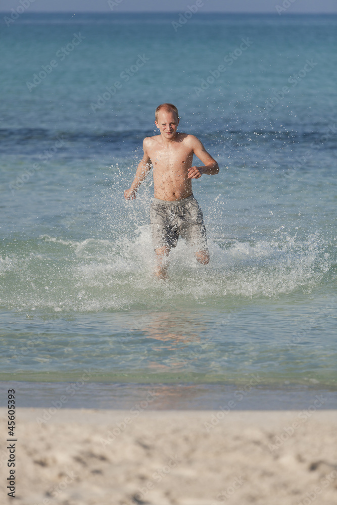 mann rennt am strand im Wasser Hochformat