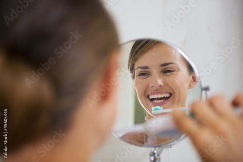 Happy woman brushing teeth with electric toothbrush photo