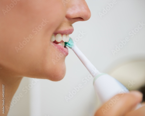 Closeup on woman brushing teeth with electric toothbrush photo