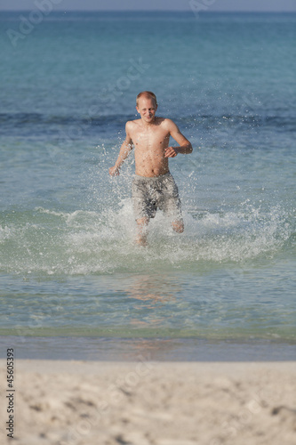 mann rennt am strand im Wasser Hochformat