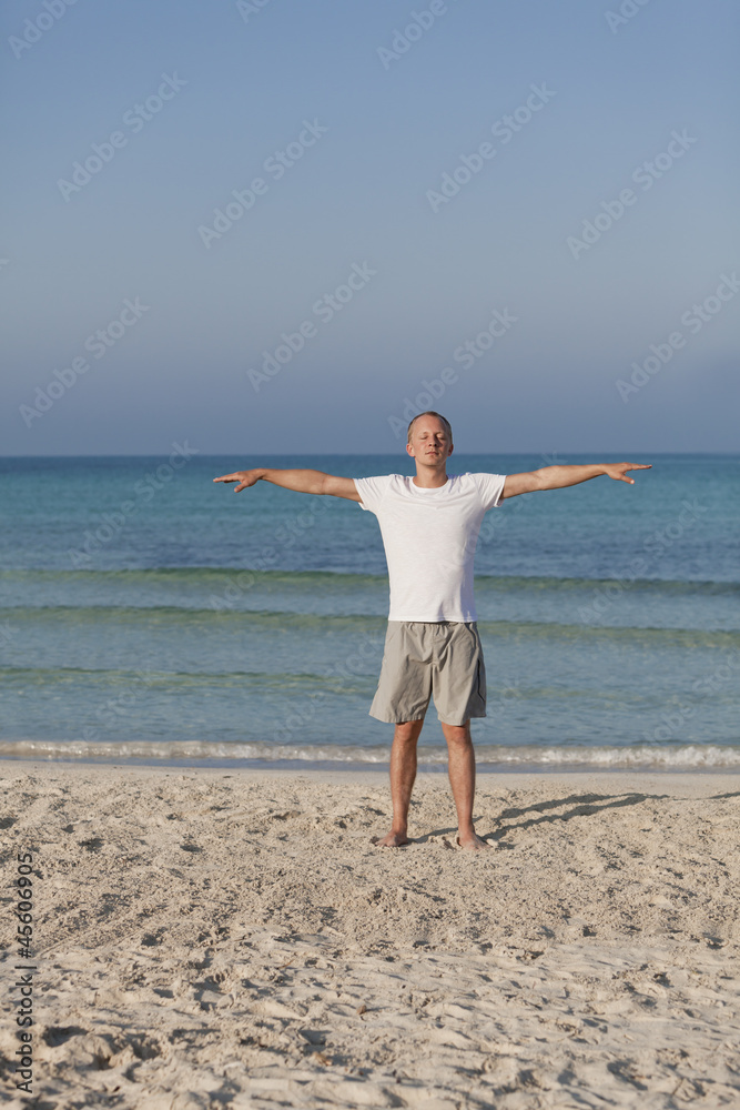 Mann macht yoga Sport am Strand Hochformat