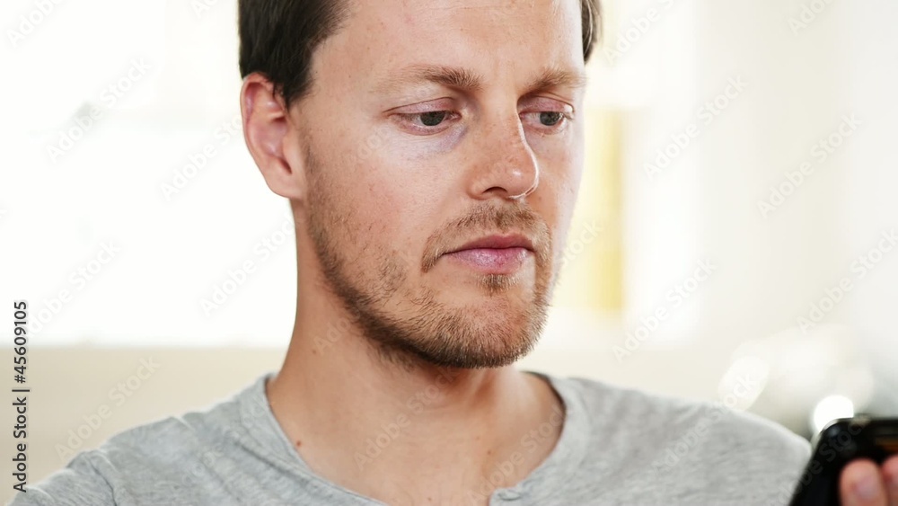 Attractive young man sending text message using mobile phone