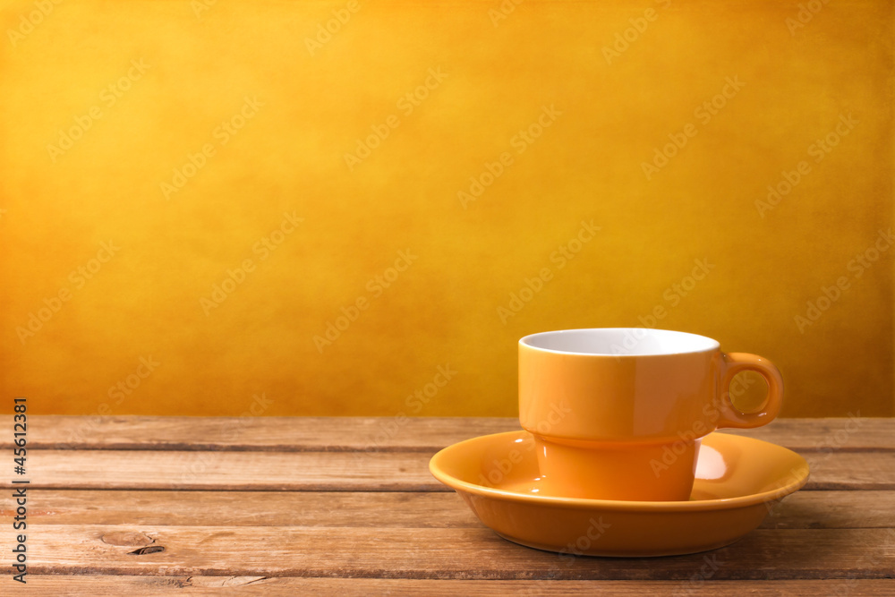 Yellow coffee cup on wooden tabletop - obrazy, fototapety, plakaty 