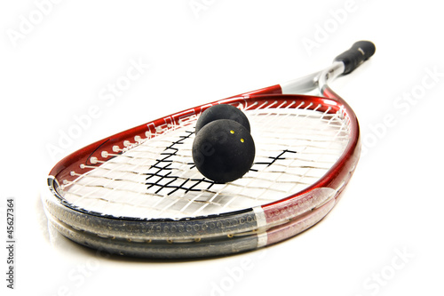 Close up of a squash racket and balls on white