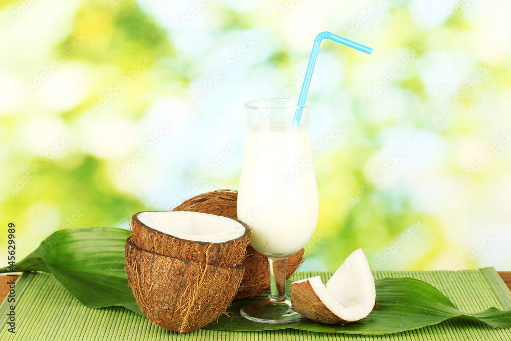 glass of coconut milk and coconuts on green background close-up glass of coconut milk and coconuts on green background close-up