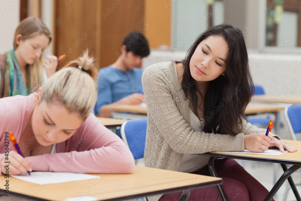 Girl copying another students work in exam Girl copying another students work in exam