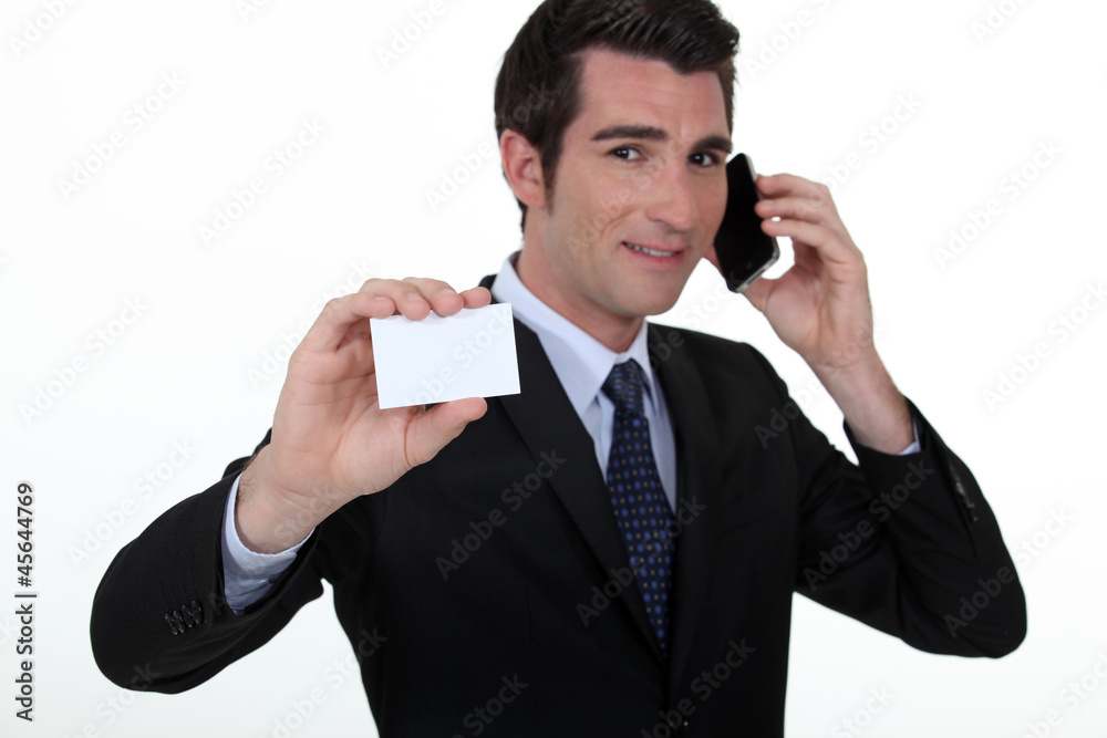 Businessman on the phone whilst showing a blank card Businessman on the phone whilst showing a blank card