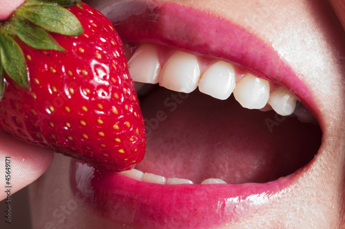 female mouth eating a fresh strawberry