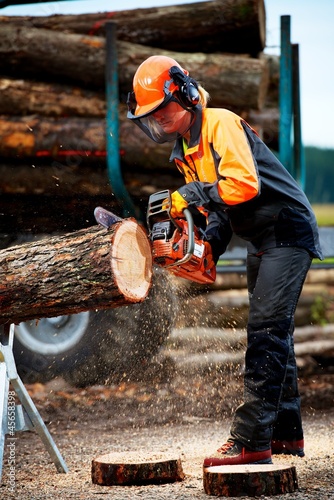 Junge attraktive Frau schneidet mit Motorsäge