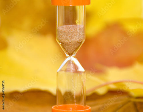 Background of autumn leaves and sandglass