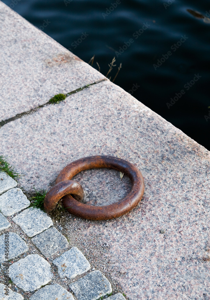 Metal mooring ring on the stone coast Metal mooring ring on the stone coast