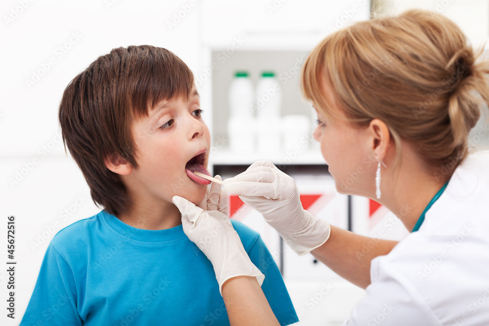 Doctor checking the throat of a young boy