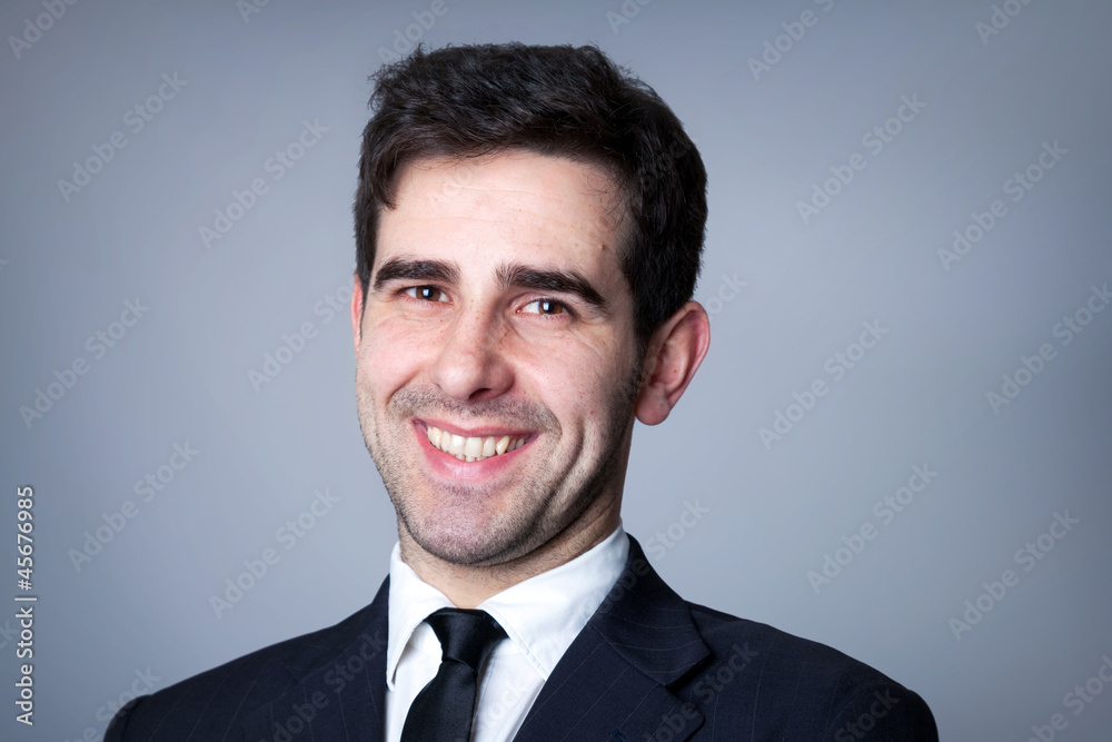 Close-up portrait of a smiling young business man on grey backgr Close-up portrait of a smiling young business man on grey backgr