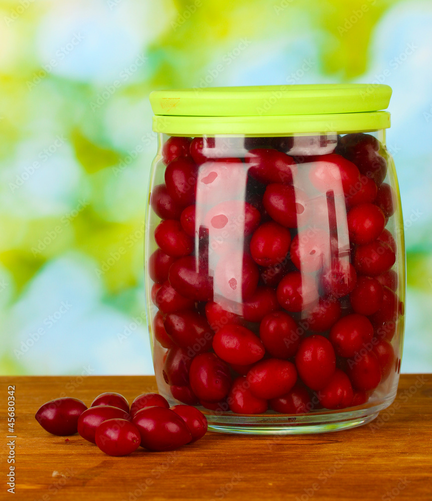 fresh cornel berries in glass jar on green background close-up fresh cornel berries in glass jar on green background close-up
